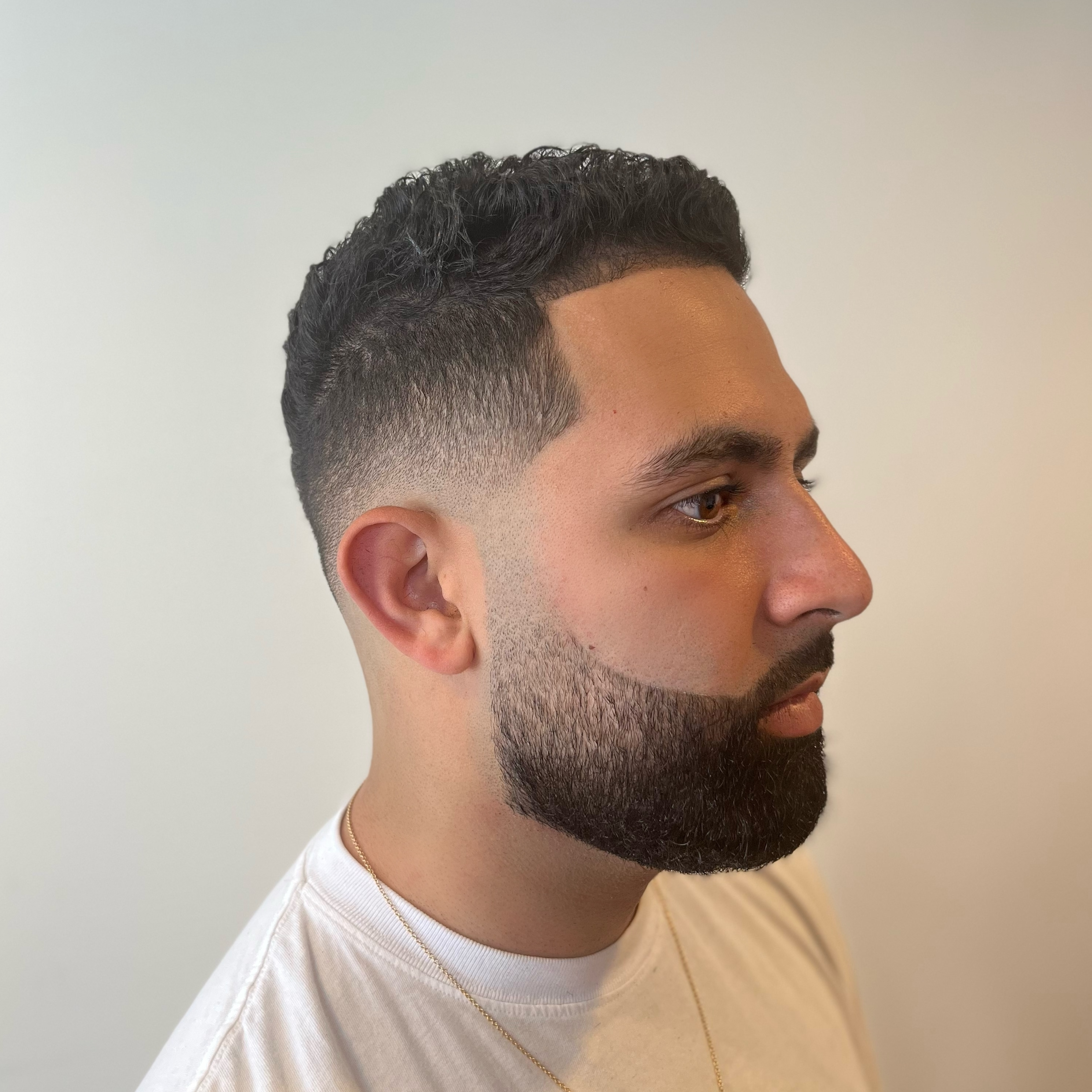 Man with low fade, textured crop haircut using andis clippers, and trimmed full beard and moustache.