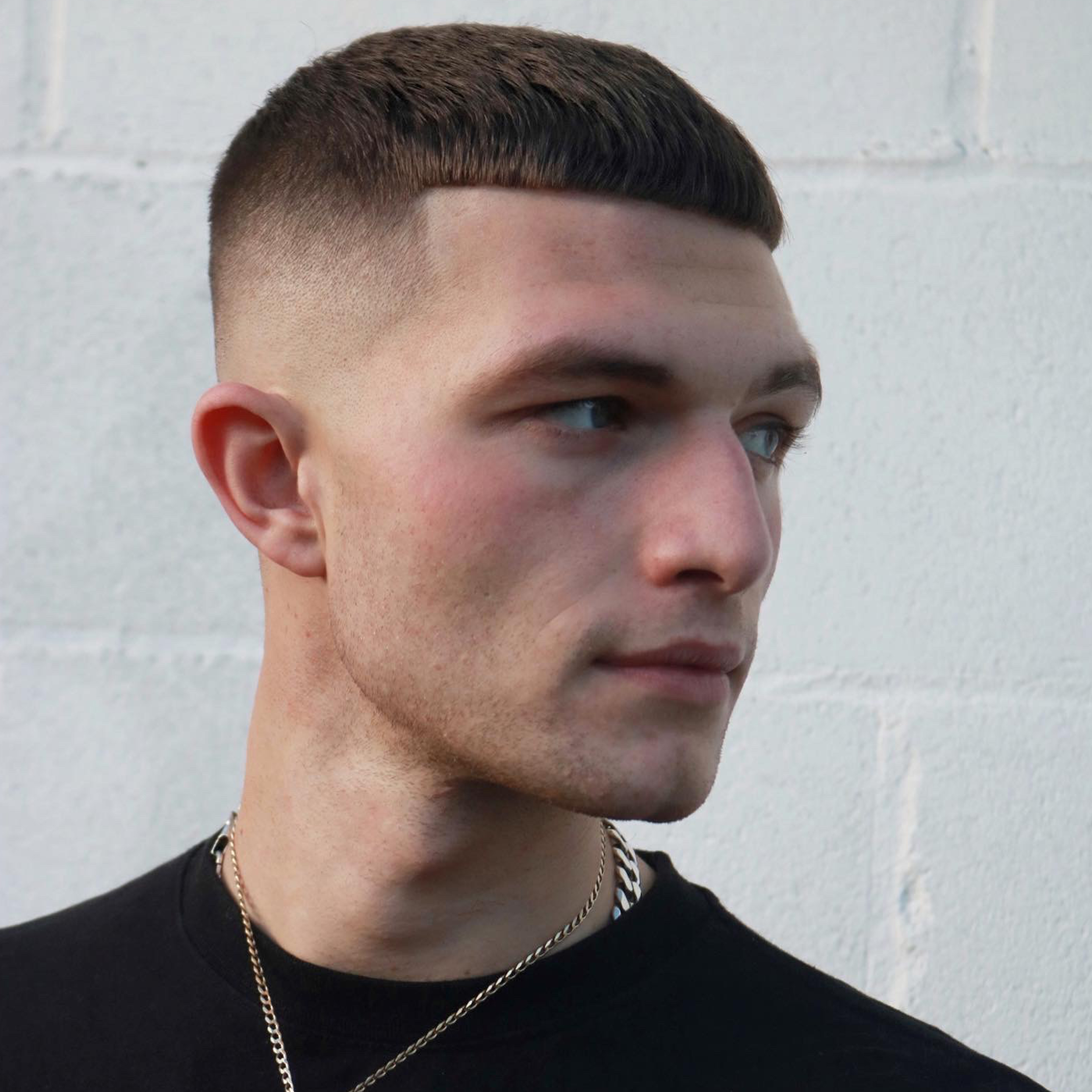 Caucasian male in a black t-shirt with a high fade created using Andis clippers and trimmers.