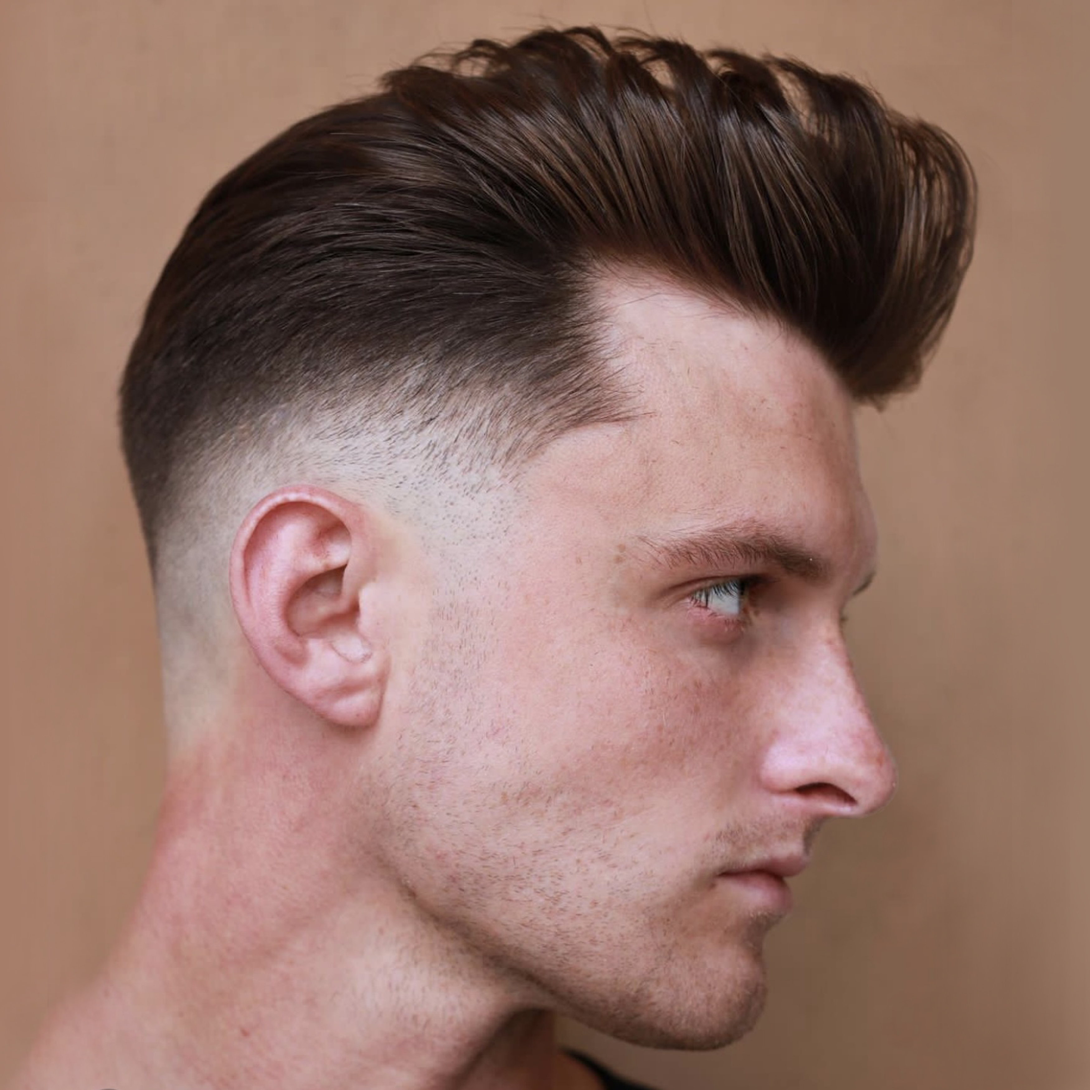 Male with voluminous pompadour hair style and mid fade designed by Andis clippers and trimmers.