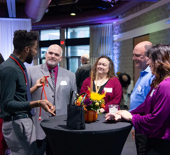 5 Andis employees standing at a circular table and talking